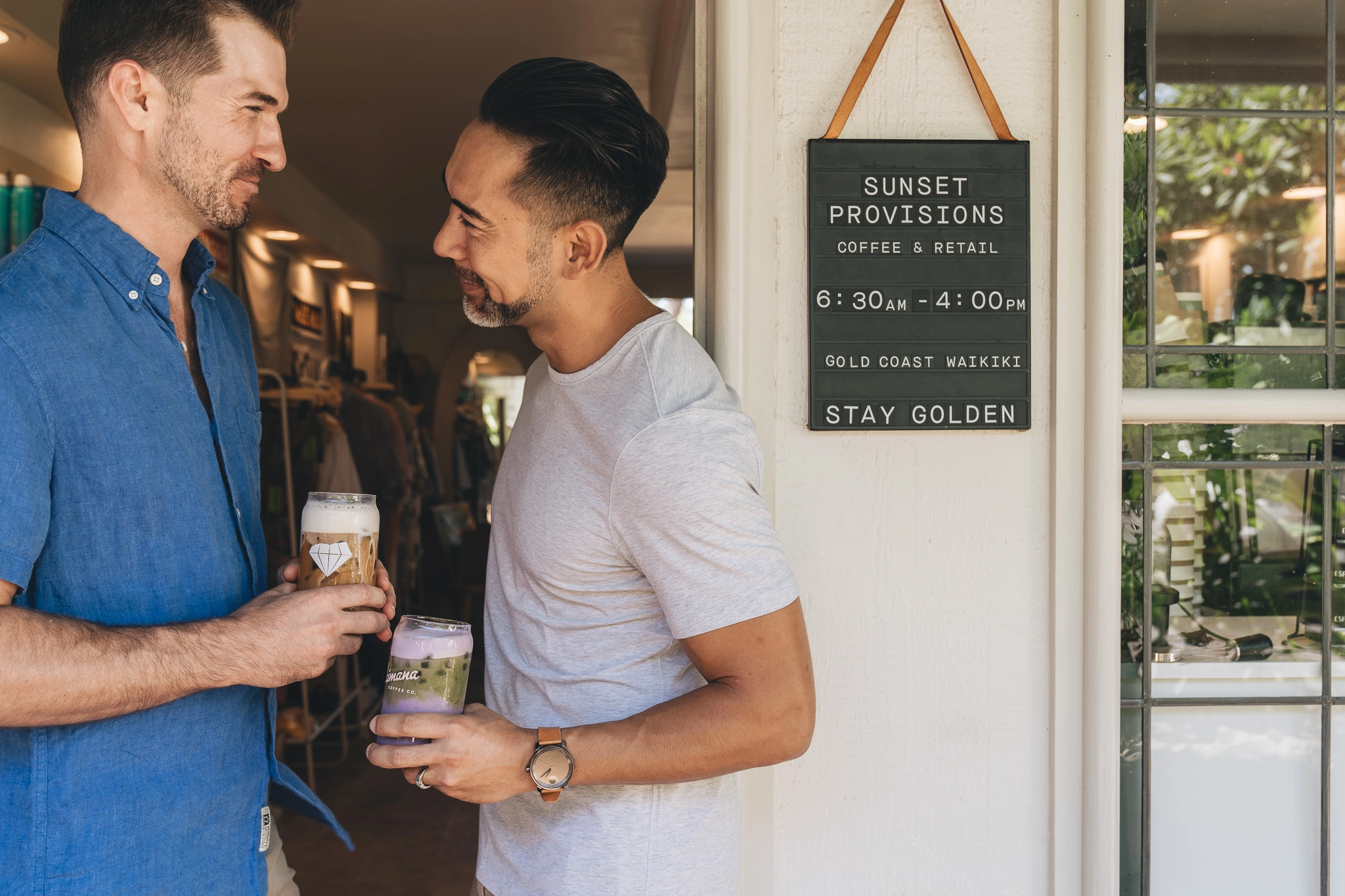 Couple holding colorful iced coffees outside of Sunset Provisions cafe