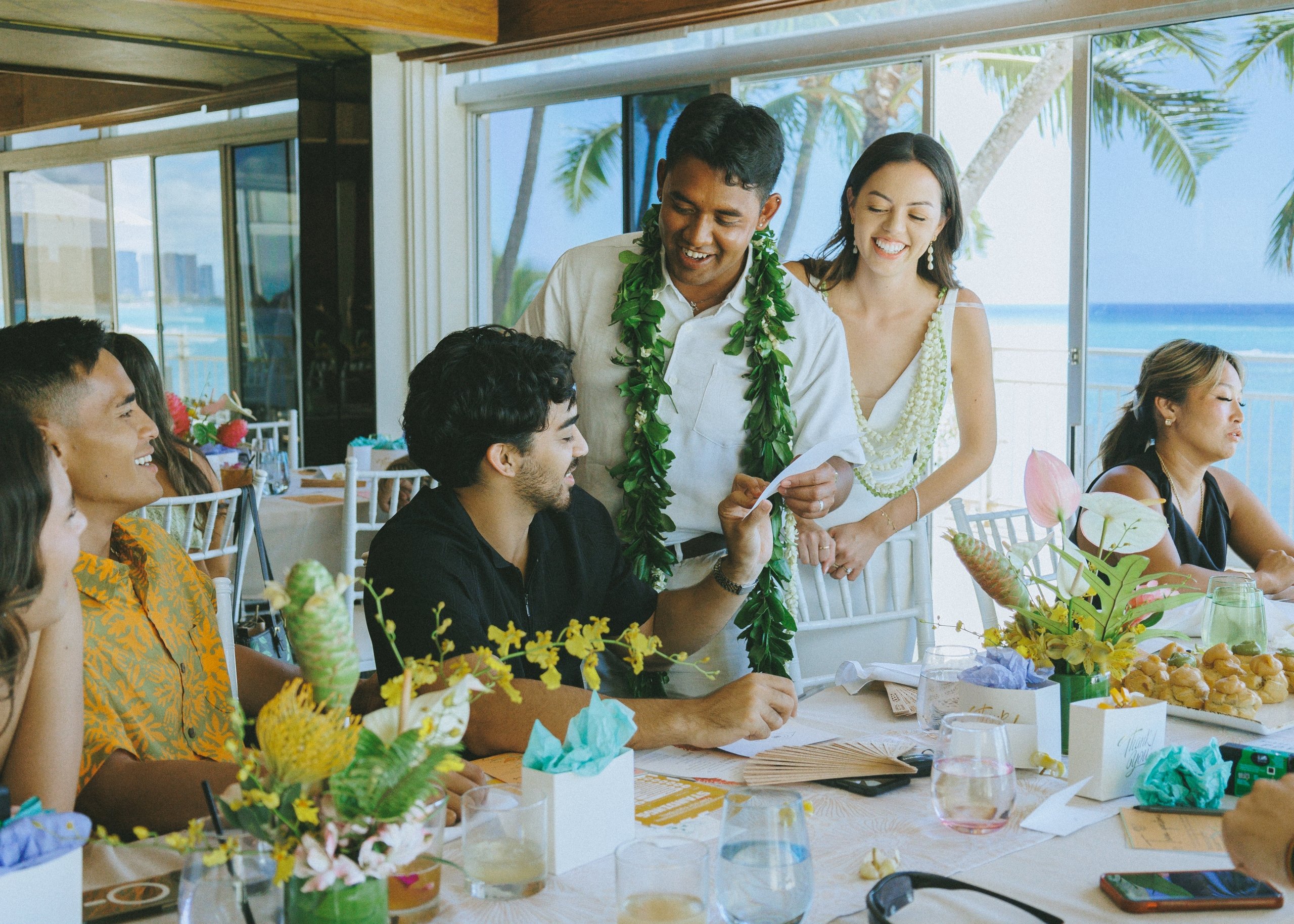 Guests sit around a table taking part in wedding festivities