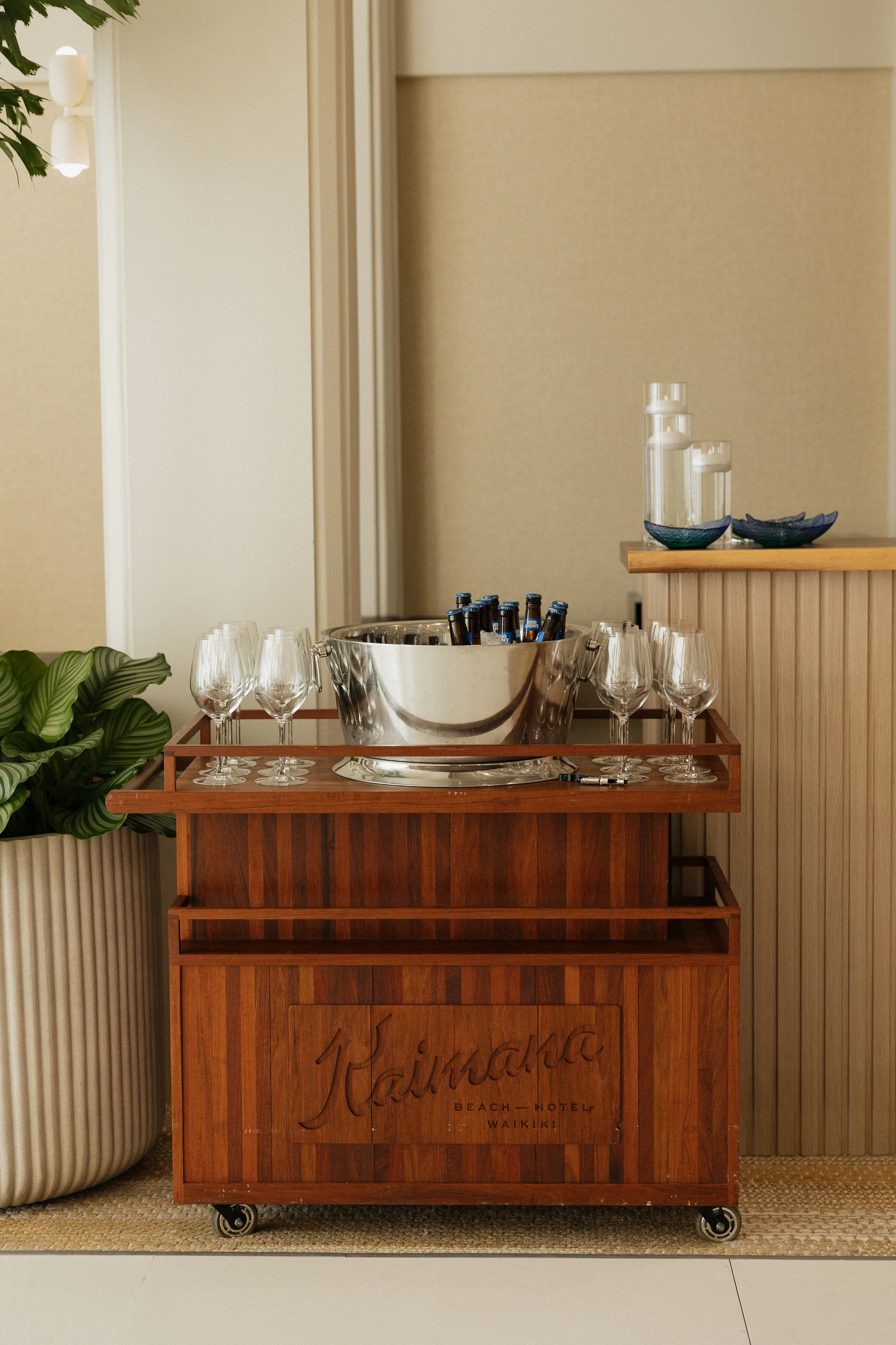 Wooden bar cart complete with rows of empty glasses and a bucket full of champagne